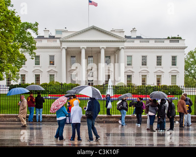 Le port d'imperméables et de parapluies, transportant les touristes se rassemblent devant la Maison Blanche à Washington, D.C. Banque D'Images