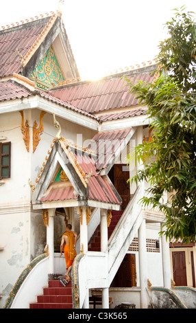 Un moine en robe orange monte escalier au Wat Xian Nyeun, temple bouddhiste, Vientiane, Laos Banque D'Images