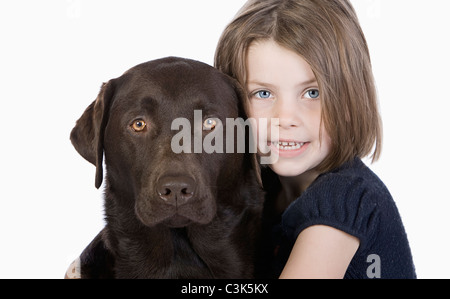 Studio portrait of smiling girl (6-7) hugging labrador chocolat Banque D'Images