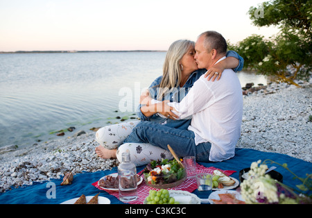 Mature couple having picnic on beach Banque D'Images