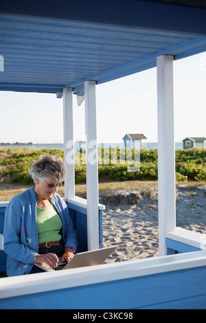 Senior woman using laptop in echelle hut Banque D'Images