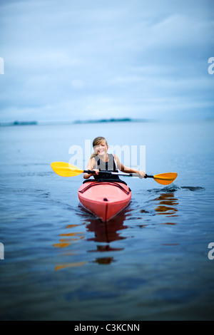 Woman rowing canoe on lake, smiling Banque D'Images