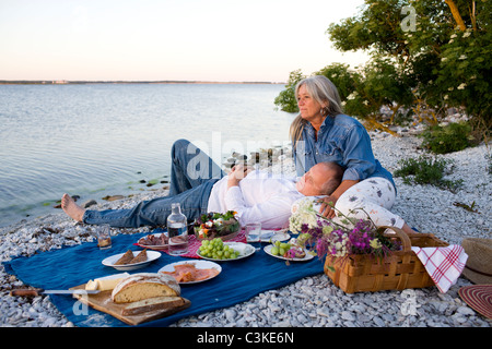 Mature couple having picnic on beach Banque D'Images