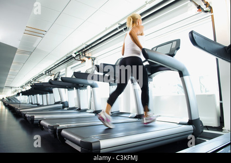 Femme exerçant sur tapis roulant dans une salle de sport Banque D'Images