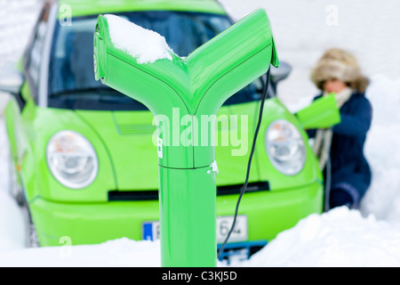 Jeune femme voiture électrique de charge Banque D'Images