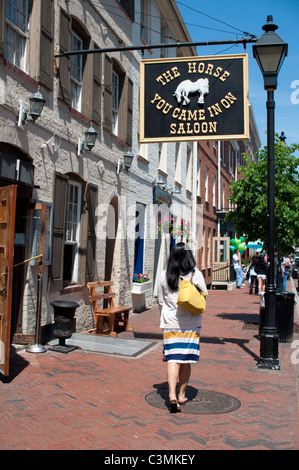 Une jeune femme marche par le cheval que vous est venu dans le Saloon dans le quartier Fells Point de Baltimore, Maryland, USA. Banque D'Images