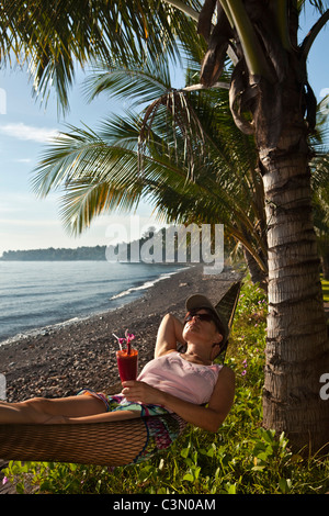 L'Indonésie, île de Bali, près de Tejakula, Gaia Village Oasis Resort. Les femmes dans l'hamac. Banque D'Images