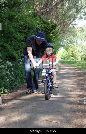 Jeune garçon d'apprendre à faire du vélo Banque D'Images