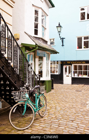 Bicyclette verte au bas de l'escalier en fer forgé par Crooked House, Market Street une rue pavée à Windsor, England, UK Banque D'Images