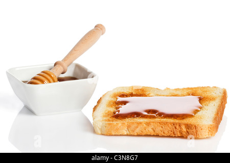 Pain grillé avec du miel un pot de miel Le miel d'un balancier sur fond blanc Banque D'Images