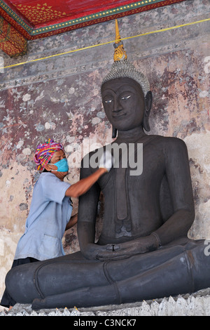 Polissage d'un artisan en statue de Bouddha noire Wat Suthat temple à Bangkok, Thaïlande. Banque D'Images