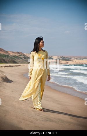 Young Asian Woman in yellow ao dai sur la plage Banque D'Images