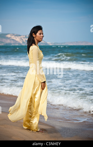 Young Asian Woman in yellow ao dai sur la plage Banque D'Images