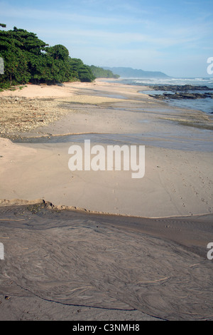 Une rivière coule à travers la plage de sable blanc. Puntarenas, Costa Rica, Amérique Centrale Banque D'Images