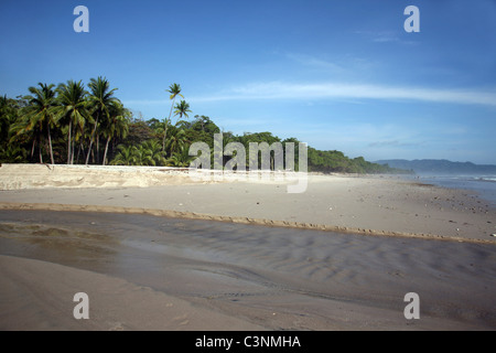 Une rivière coule à travers la plage de sable blanc à Puntarenas, Costa Rica, Amérique Centrale Banque D'Images