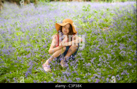 Une fille assise à Bluebells Banque D'Images