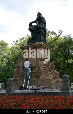 Un peintre à retoucher la peinture or sur l'inscription sur une statue dans le Vondelpark, le principal parc d'Amsterdam, Pays-Bas. Banque D'Images