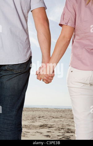 Allemagne, Schleswig Holstein, Amrum, Couple holding hands on beach, vue arrière, mid section Banque D'Images