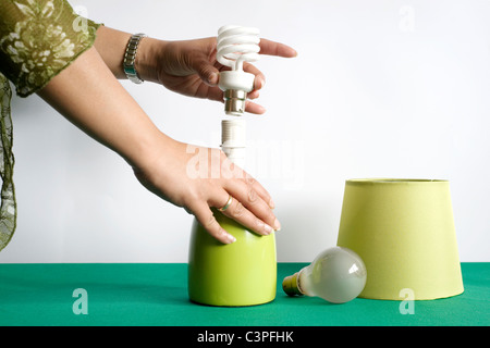 Femme changer les vieilles ampoules à incandescence traditionnelles de style dans une lampe de table pour de nouveaux ampoule de type basse énergie Banque D'Images