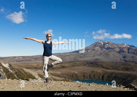 Nouvelle Zélande, île du Nord, woman doing exercise au parc national de Tongariro avec mount ruapehu en arrière-plan Banque D'Images