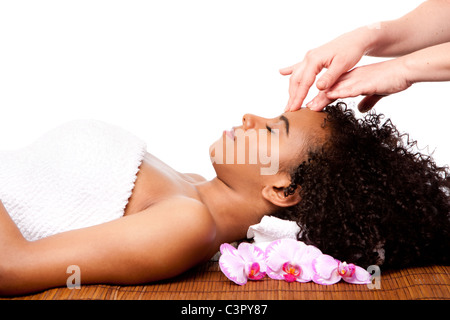 Femme brésilienne au spa de jour, portant sur bambou table de massage avec la tête sur l'oreiller portant une serviette d'obtenir un massage facial. Banque D'Images