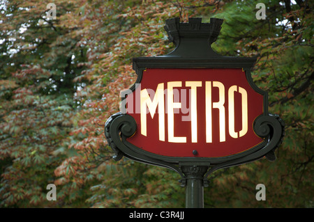 Un emblématique panneau Art Nouveau Métro parisien, sur fond de feuillage, dans l'avenue des champs Elysées. Paris, France. Banque D'Images