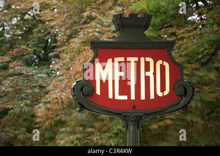 Un emblématique panneau Art Nouveau Métro parisien, sur fond de feuillage, dans l'avenue des champs Elysées. Paris, France. Banque D'Images