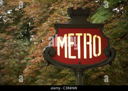 Un emblématique panneau Art Nouveau Métro parisien, sur fond de feuillage, dans l'avenue des champs Elysées. Paris, France. Banque D'Images