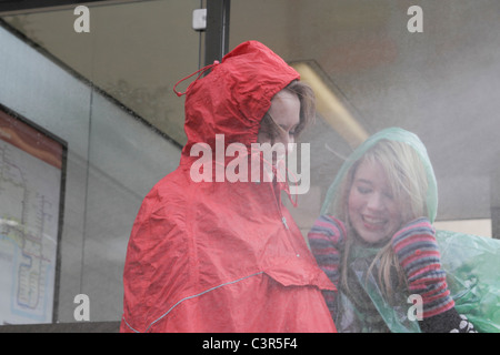 2 femmes à l'arrêt de bus sous la pluie Banque D'Images