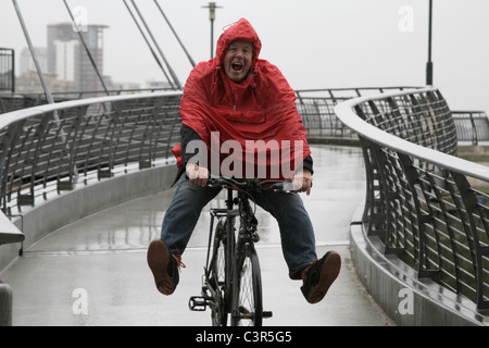 L'homme dans la pluie en vélo s'amusant Banque D'Images