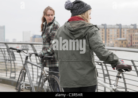 2 jeunes femmes poussant des vélos Banque D'Images