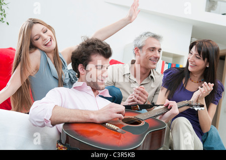 Joyeux amis jouer de la guitare à la maison Banque D'Images