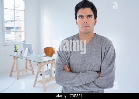 Homme debout dans un bureau les bras croisés Banque D'Images