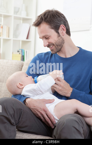 Germany, Bavaria, Munich, père de lait d'alimentation pour bébé garçon (6-11 mois) dans la salle de séjour Banque D'Images