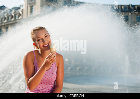 Allemagne, Munich, Karlsplatz, young woman eating ice cream Banque D'Images