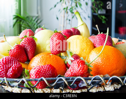 Une corbeille de fruits dans la salle de séjour avec des fraises, pommes, poires, oranges, bananes, citron Banque D'Images
