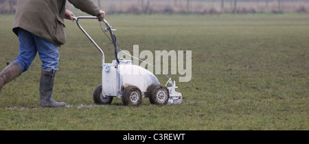 Groundsman peinture des lignes blanches sur un terrain de football à l'aide d'une poussée le long de la machine Banque D'Images