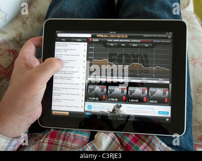 L'homme contrôle de la performance des marchés boursiers à l'aide de Fox Business app sur un écran tactile iPad tablet computer Banque D'Images