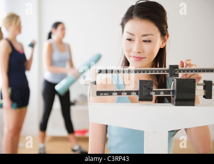 Femme asiatique elle-même sur l'échelle de pesage Banque D'Images