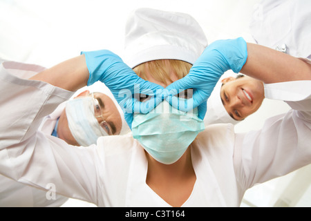 Droit de l'infirmière en gardant ses mains gantées masque devant ses yeux avec nos collègues de l'arrière-plan Banque D'Images