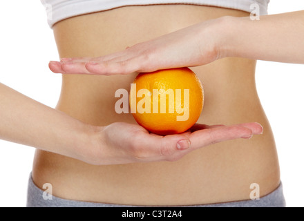 Close-up of female hands holding une orange en face de ventre Banque D'Images