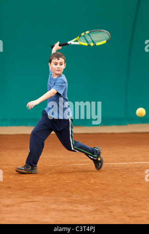 Garçon jouant au tennis sur le court de l'écume Banque D'Images