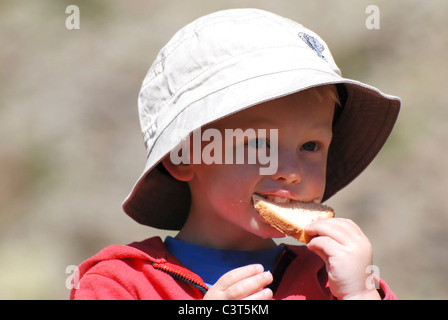 Un jeune garçon est assis de déguster une boisson et un pique-nique à Kreuzboden dans la vallée de Saas, la Suisse. Banque D'Images