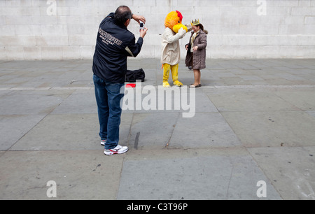 Un interprète dans un costume d'oiseau fait un plaisir de poser pour les touristes à Londres contre un fond uni Banque D'Images