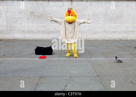 Un interprète dans un costume d'oiseau fait un heureux poser contre un fond uni Banque D'Images