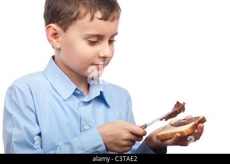 Closeup portrait of a Boy diffusion de chocolat ou de beurre d'arachide sur tranche de pain Banque D'Images