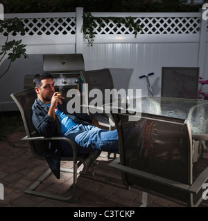 Young man drinking wine et tabagisme on patio Banque D'Images