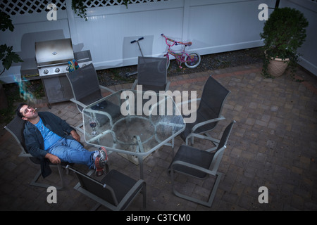 Young man drinking wine et tabagisme on patio Banque D'Images