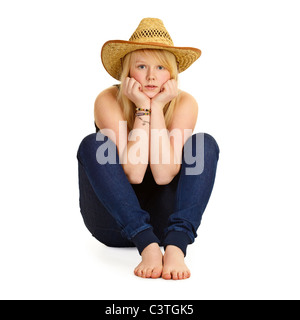 Une jeune blonde dans un chapeau de paille assis sur le plancher isolé sur fond blanc Banque D'Images