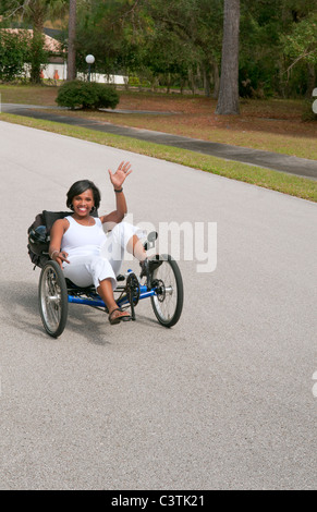 Femme noire ayant du plaisir de conduire le plus récent appelé Terre machince vert un Trike tricycle couchés autour de sur la route pour l'excitation Banque D'Images